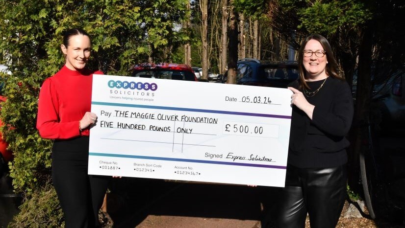 Two women holding a large cheque outside