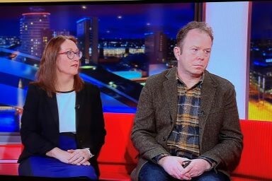 Man and woman sat next to each other on sofa on news show