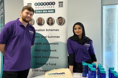 Two people stood by a table at law fair